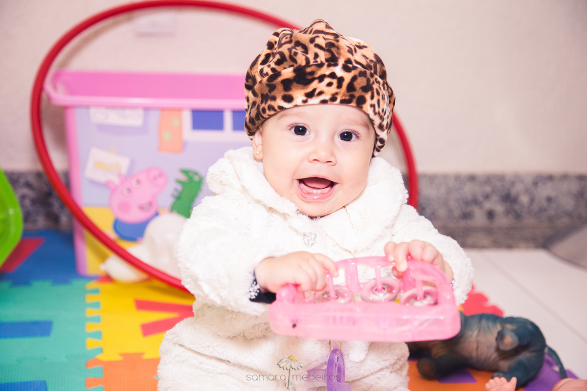 Criança bebê sentada no chão brincando durante uma festa de aniversário infantil em Belo Horizonte.