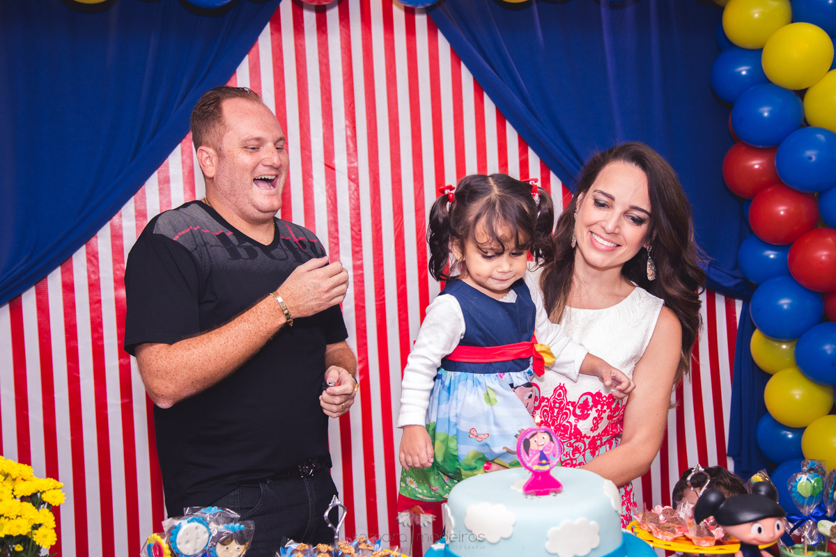 Criança e pais na mesa do bolo durante o parabéns, no aniversário de 2 anos.