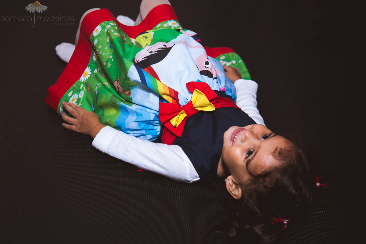 Criança deitada na cama elástica sorrindo, brincando em sua festa de aniversário, em Belo Horizonte.