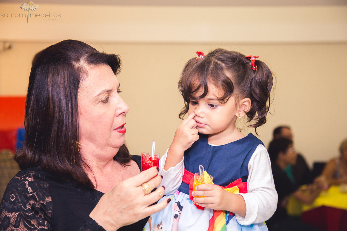Criança no colo de um adulto cutucando o nariz.