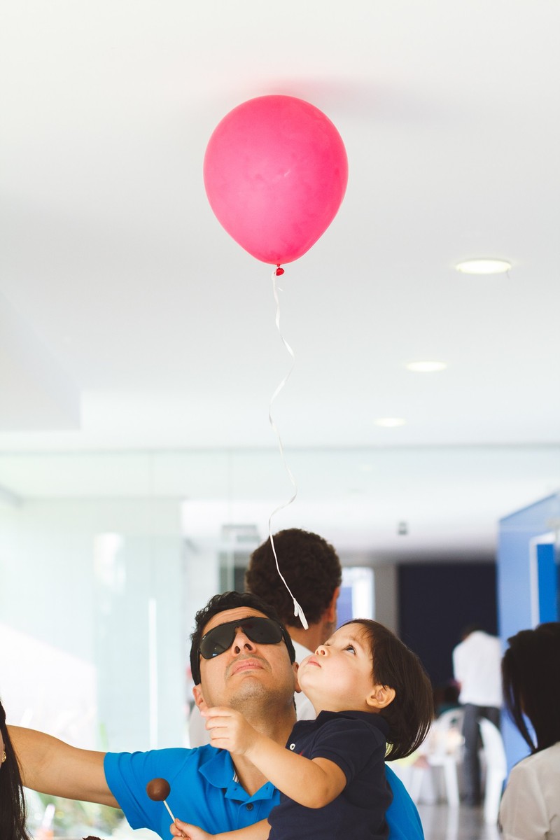 Criança olhando para o balão que saiu voando e parou no teto do salão, durante um aniversário infantil.