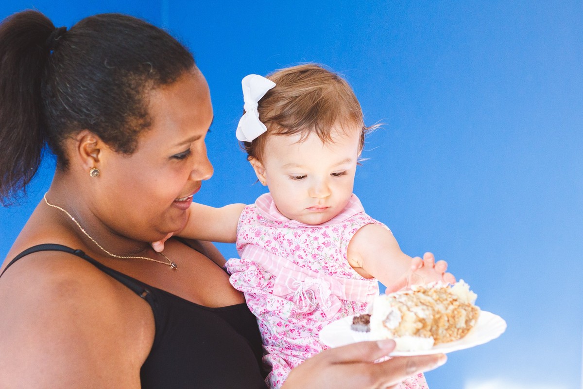 Criança olhando para um pedaço de bolo durante seu aniversário de 1 ano.