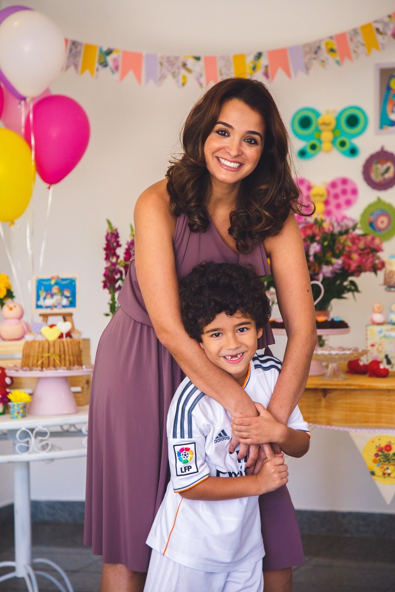 Criança com sua mãe olhando para a foto e sorrindo durante um aniversário infantil.