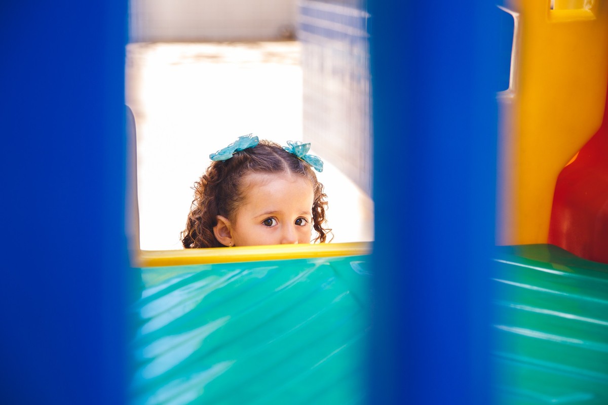 Olhos de uma criança escondida atrás de um brinquedo infantil durante um aniversário.