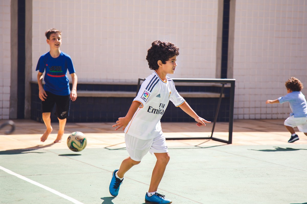 Criança comemorando um gol durante um jogo em quadra do prédio, durante um aniversário infantil.