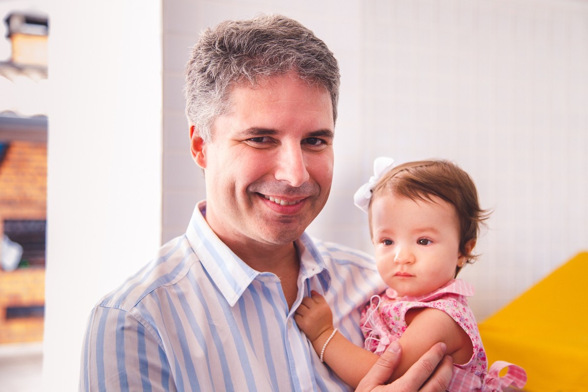 Criança no colo do seu pai, que olha para a câmera e sorri para a foto.