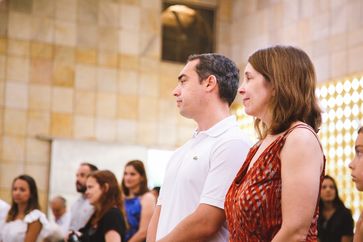 Convidados do batizado de pé, com os padrinhos da criança em primeiro plano.