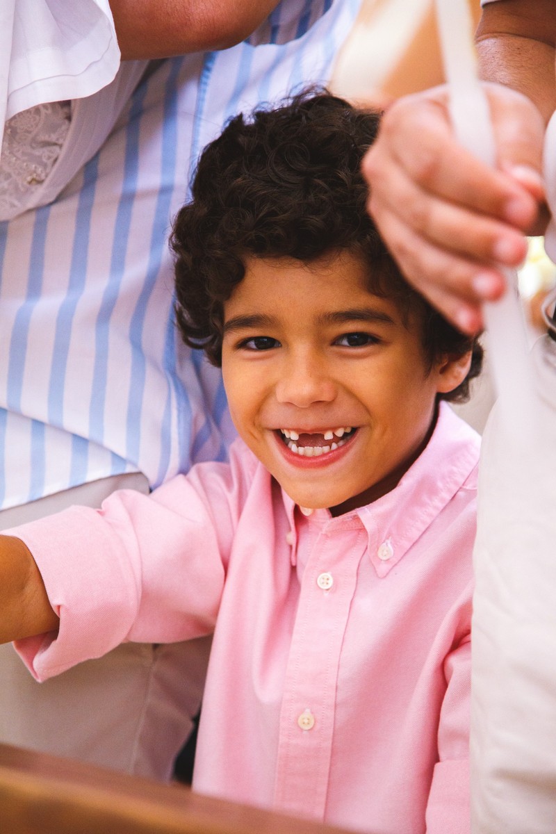 Close no rosto de uma criança na igreja enquanto acontece o batizado da irmã.
