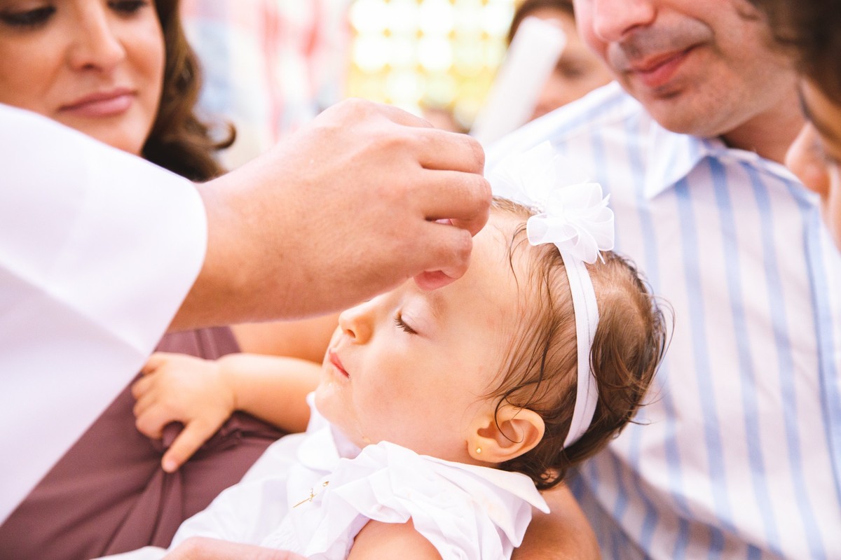 Criança recebendo bençãos durante seu batizado na igreja Santo Antônio em Belo Horizonte.