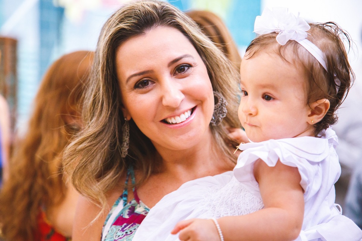 Madrinha de consagração com sua afilhada no colo, após a cerimônia de batizado em uma igreja católica.