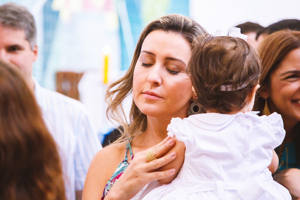 Madrinha de consagração fazendo carinho na afilhada após finalizada a cerimônia do batizado.