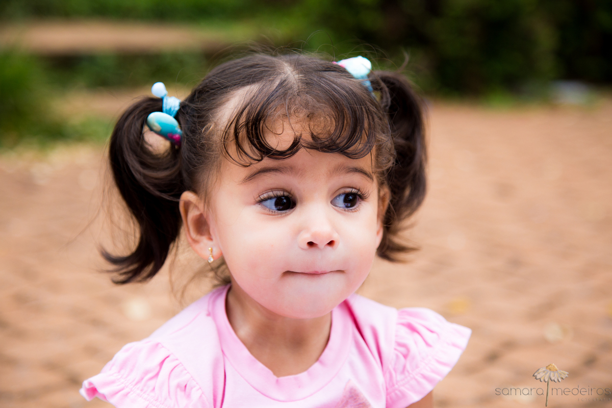 Criança brincando de fazer caretas, posando para foto em ensaio externo em Belo Horizonte.