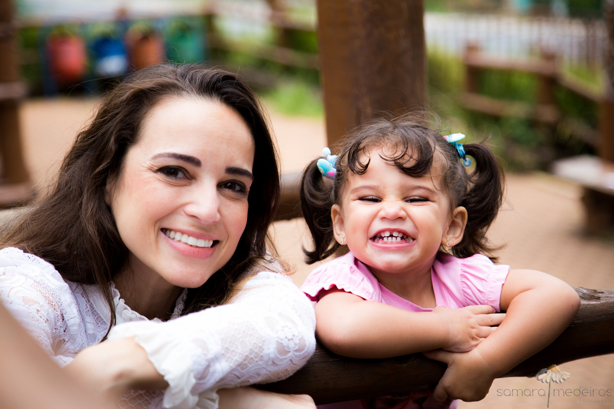 Criança fazendo careta para foto ao lado de sua mãe, que sorri.