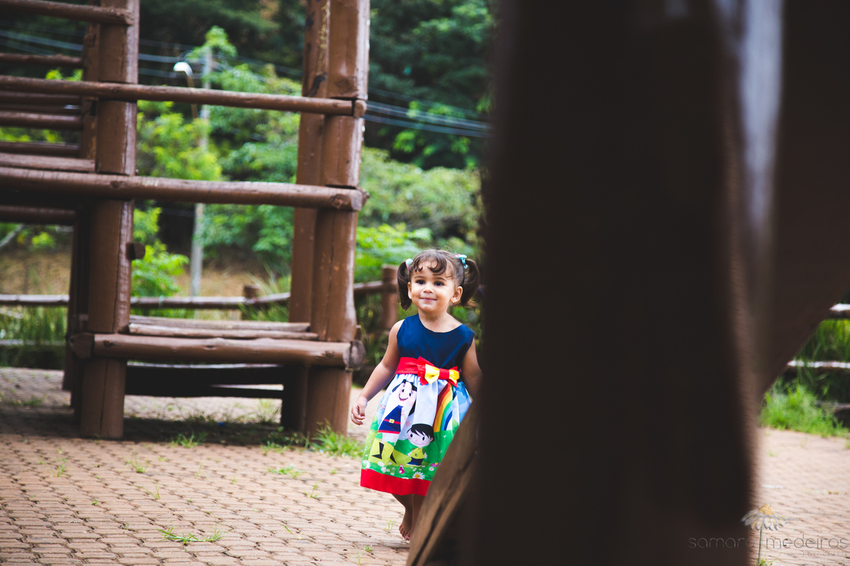 Criança brincando em meio a um parquinho feito de madeira em uma praça de Belo Horizonte, durante um ensaio fotográfico.