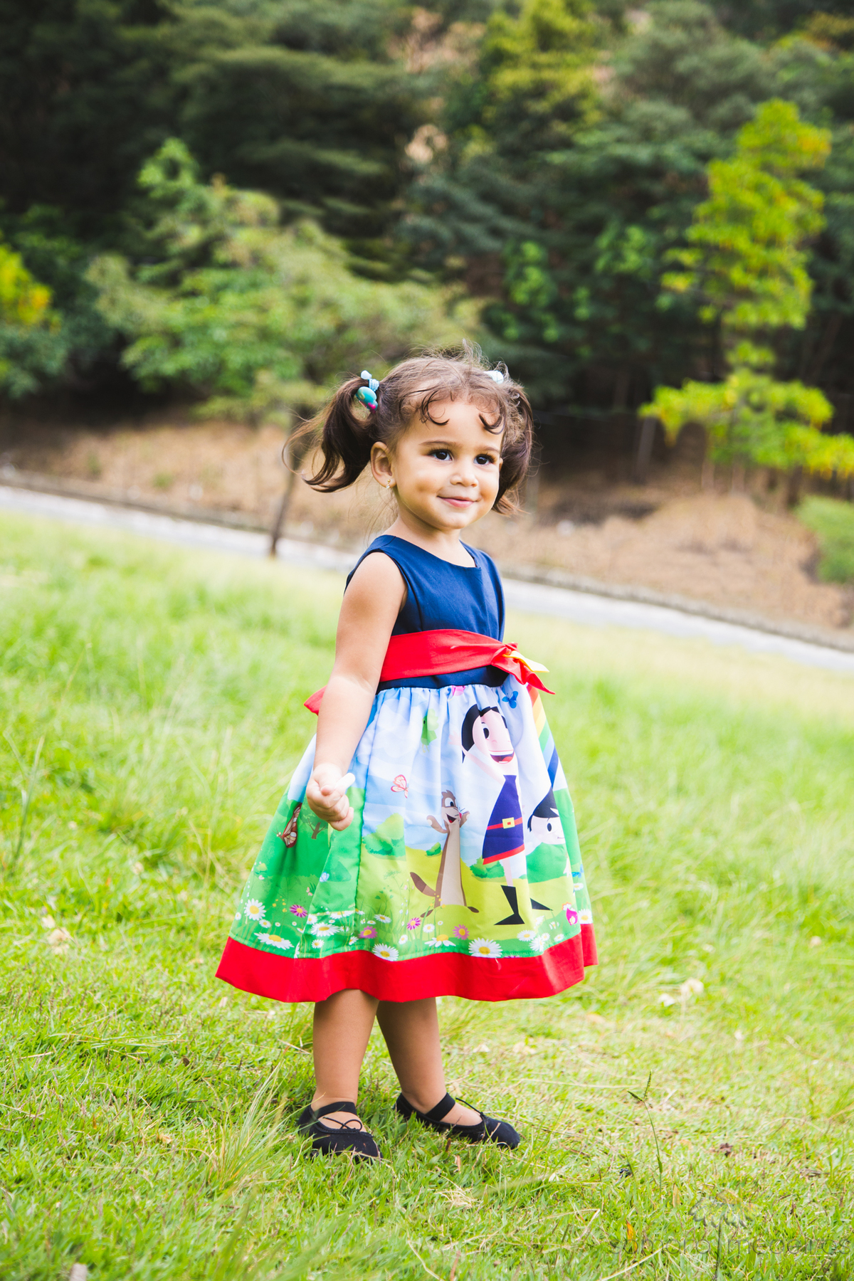 Criança brincando na grama e sorrindo durante uma sessão de fotos.