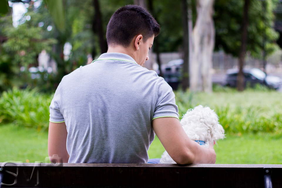 Cachorro branco e seu tutor sentados no banco de uma praça em Belo Horizonte.