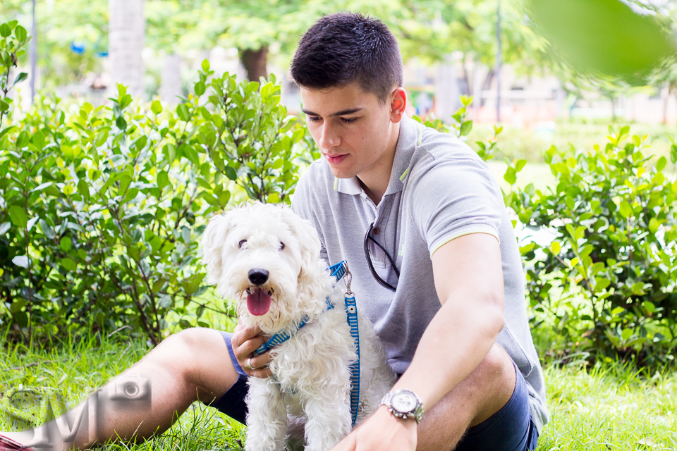 Cachorro com seu tutor sentados na grama posando para foto em praça de Belo Horizonte.