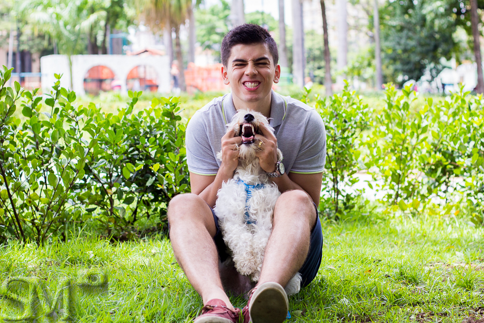 Cachorro e tutor fazendo gracinha, mostrando os dentes, para foto em ensaio externo.