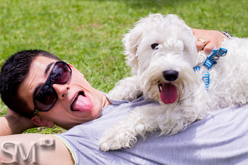 Tutor e cão mostrando a língua para foto em ensaio feito em uma praça.