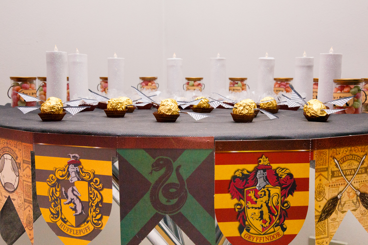 Detalhe na mesa de doces em aniversário com tema Harry Potter, com bandeirinha das casas de Hogwarts em destaque.