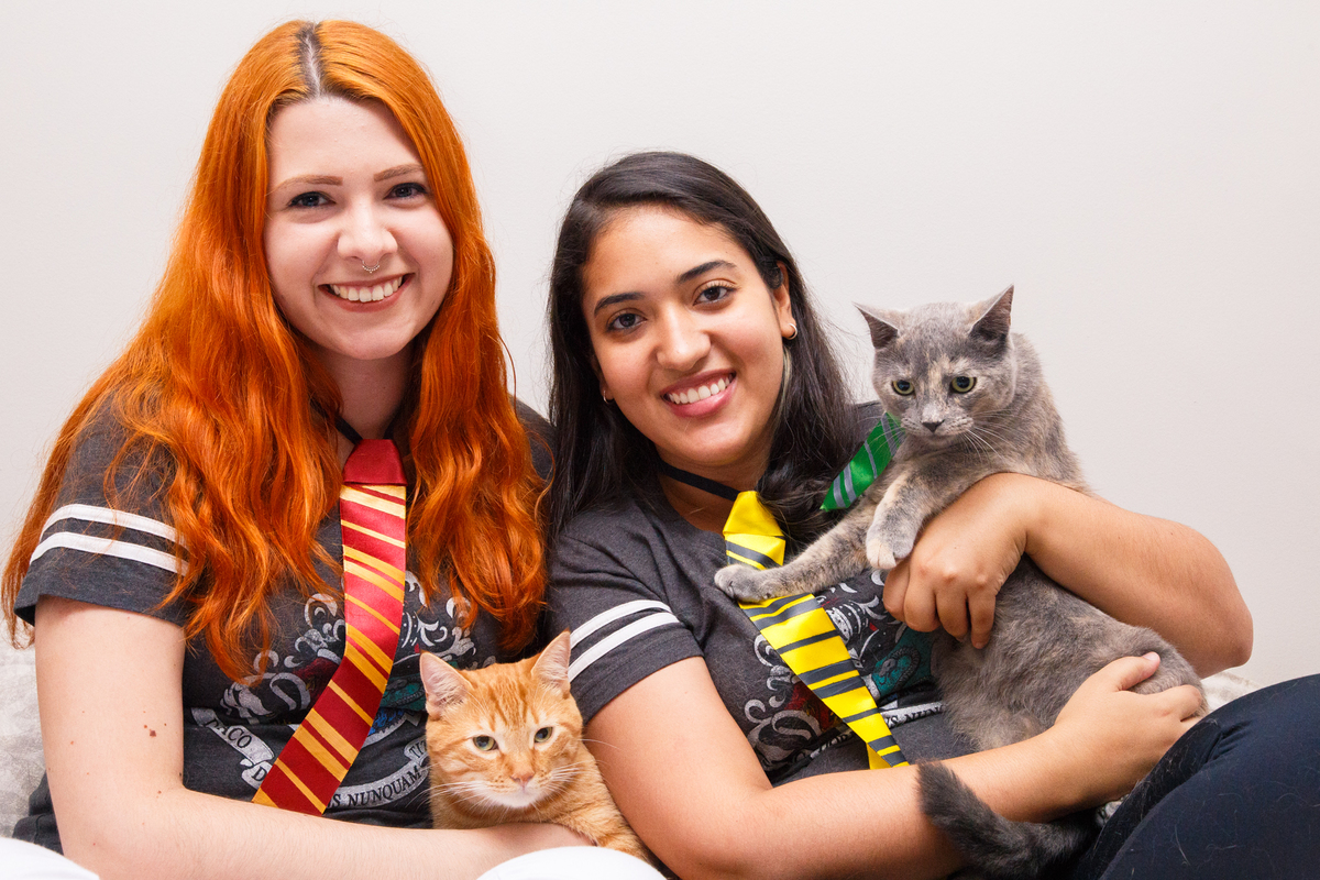 Duas tutoras com seus dois gatinhos, cada uma com um gatinho no colo, posando para a foto.