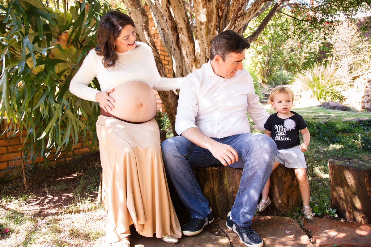 Casal sentado embaixo de uma jabuticabeira com sua filha mais velha, durante ensaio gestante.