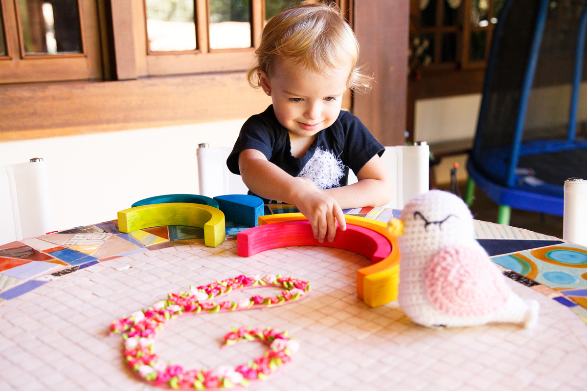 Criança brincando com a decoração do quarto de sua irmã que está para chegar.