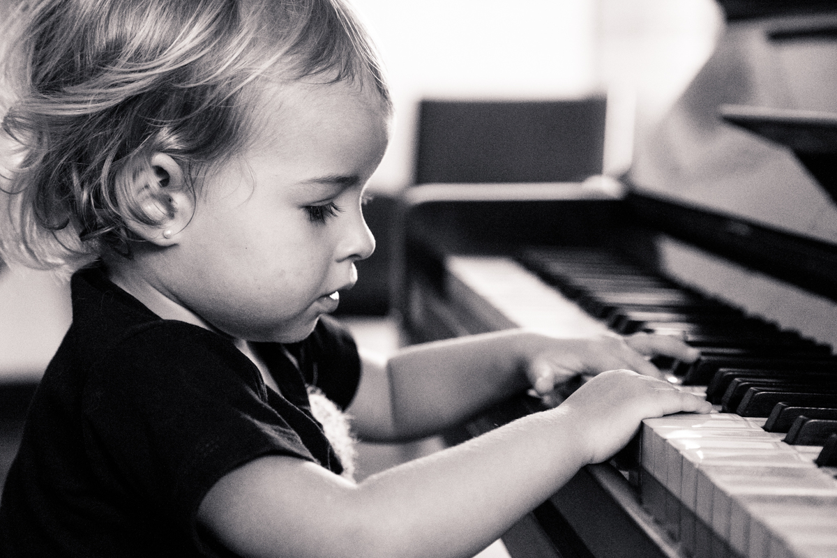 Foto em preto e branco de uma criança tocando piano.