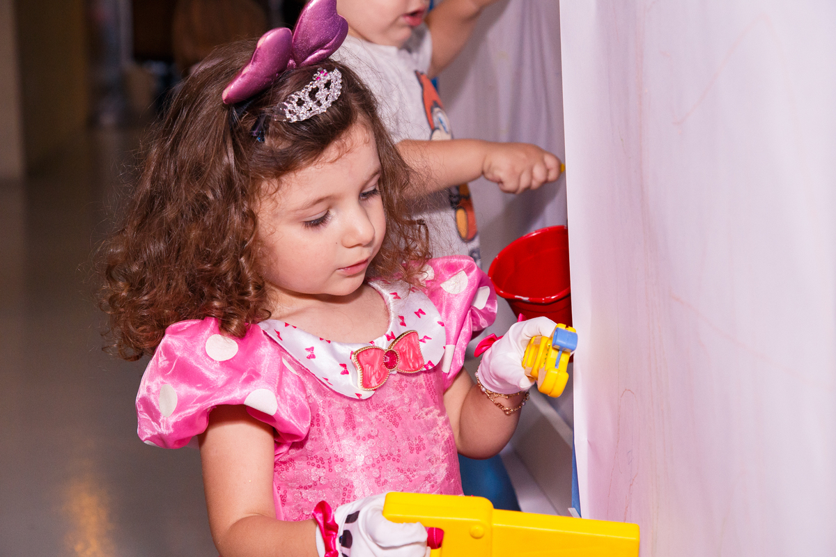 Criança brincando em seu aniversário infantil na parede de desenhos.