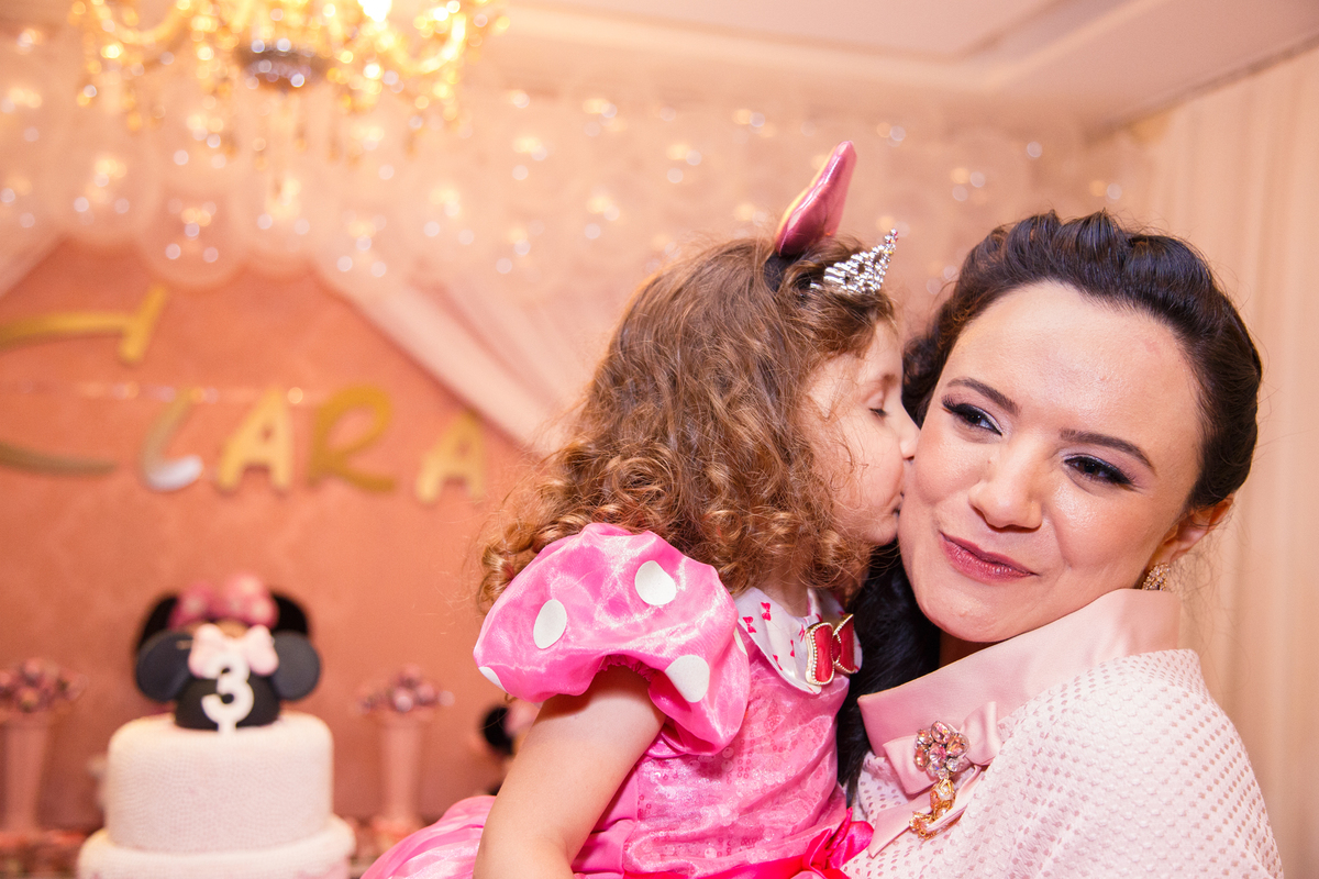 Criança em seu aniversário de 3 anos no colo mãe e dando um beijo em sua bochecha.