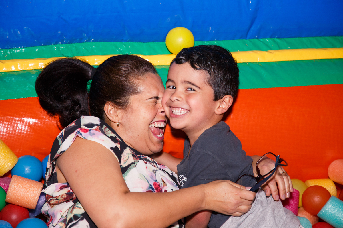 Mãe na piscina de bolinhas abraçando seu filho, irmão da criança aniversariante.