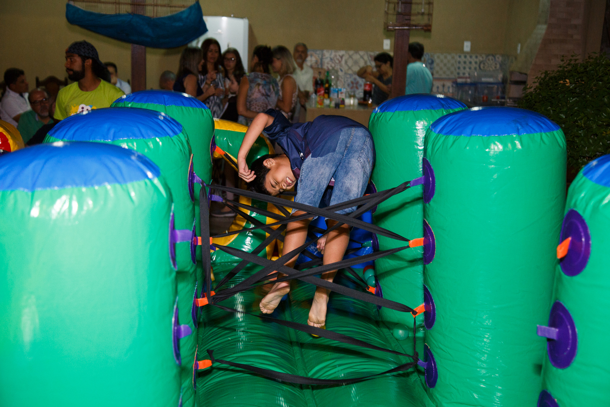 Criança brincando no brinquedão inflável em seu aniversário de 9 anos, pulando para tentar passar na parte de obstáculos.