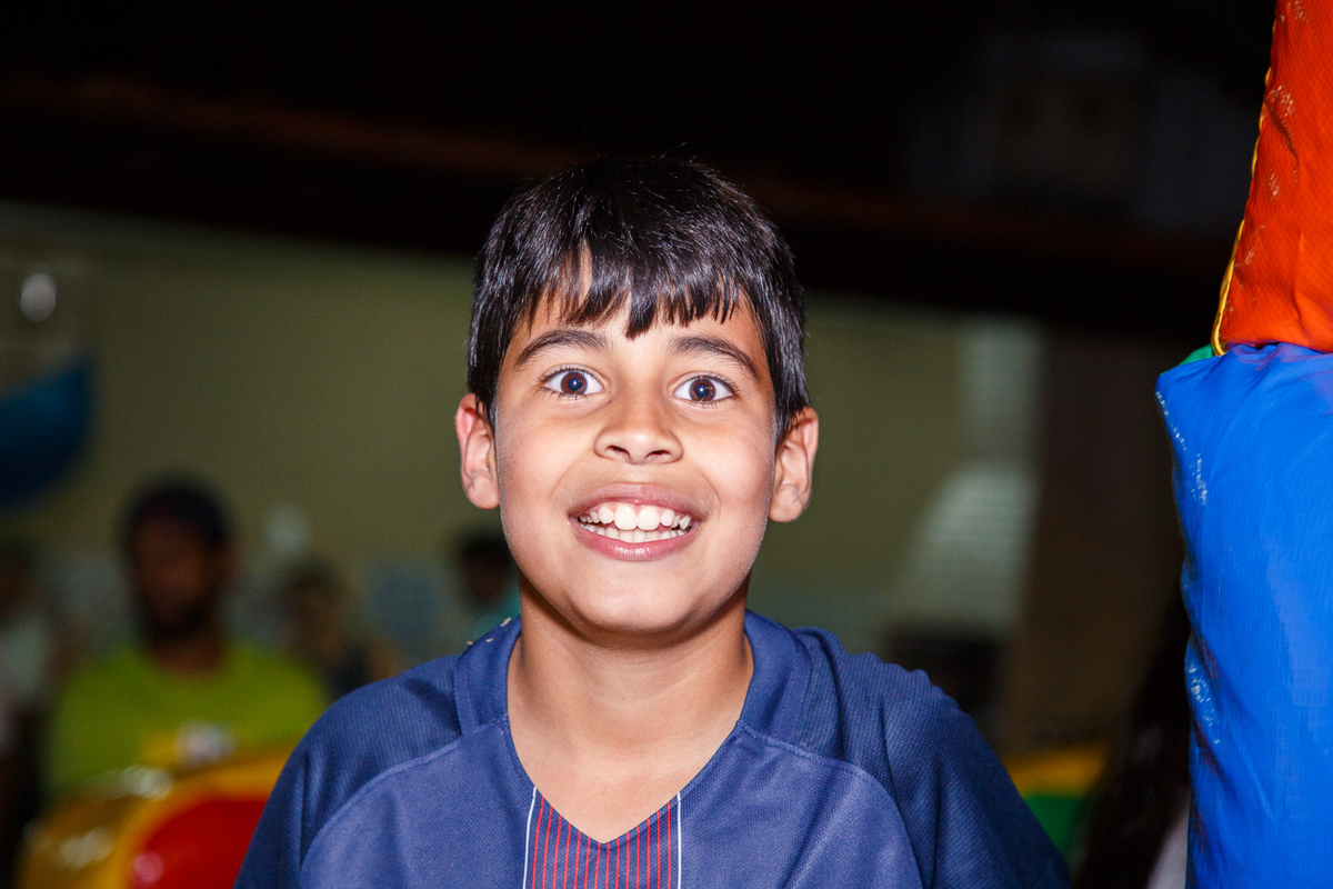 Close no rosto de uma criança, em seu aniversário de 9 anos, sorrindo.