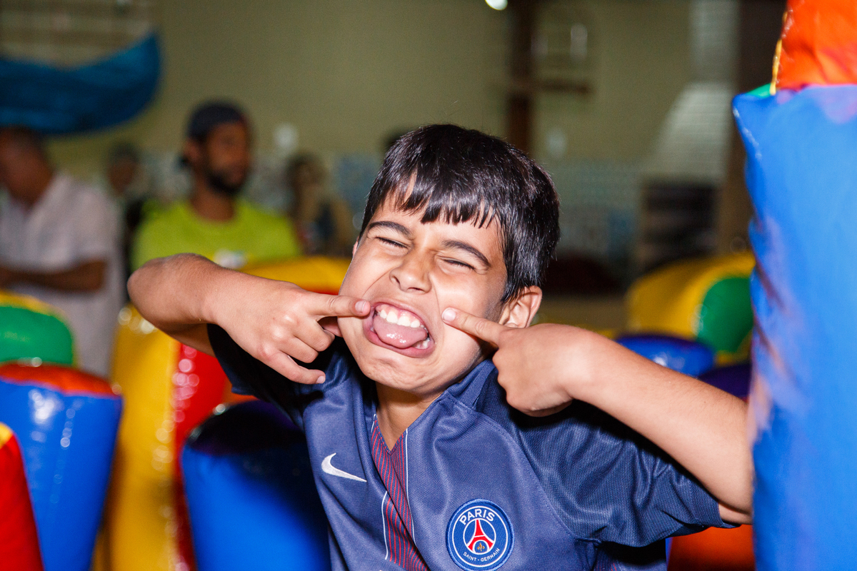 Criança em seu aniversário de 9 anos brincando, fazendo uma careta para a foto.