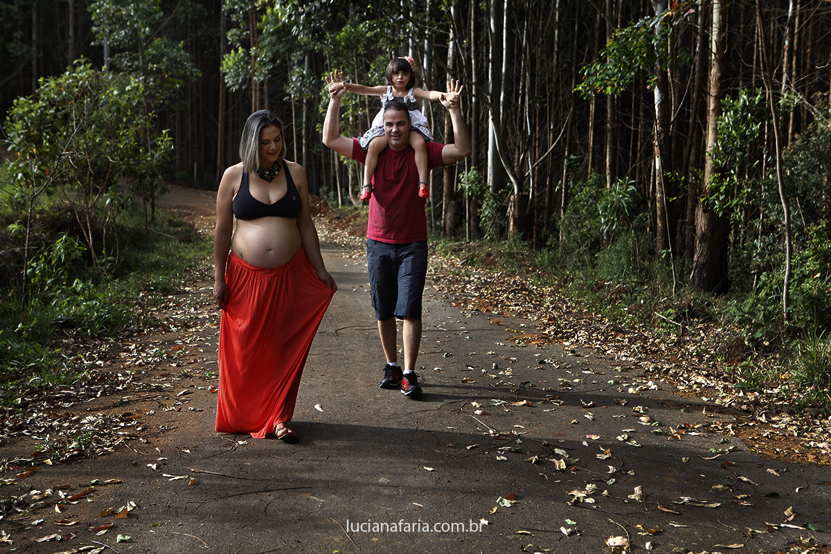 família caminhando em meio a natureza em linda tarde de fotografias externas por luciana faria fotógrafa de minas gerais e todo o brasil
