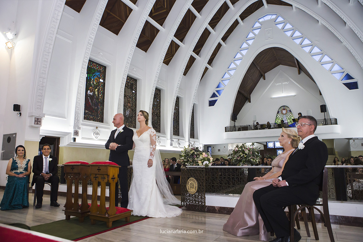 casamento de tarde na igreja são domingos em poços de caldas pais dos noivos sentados no altar na cerimônia religiosa fotografados por luciana faria fotografa de casamento