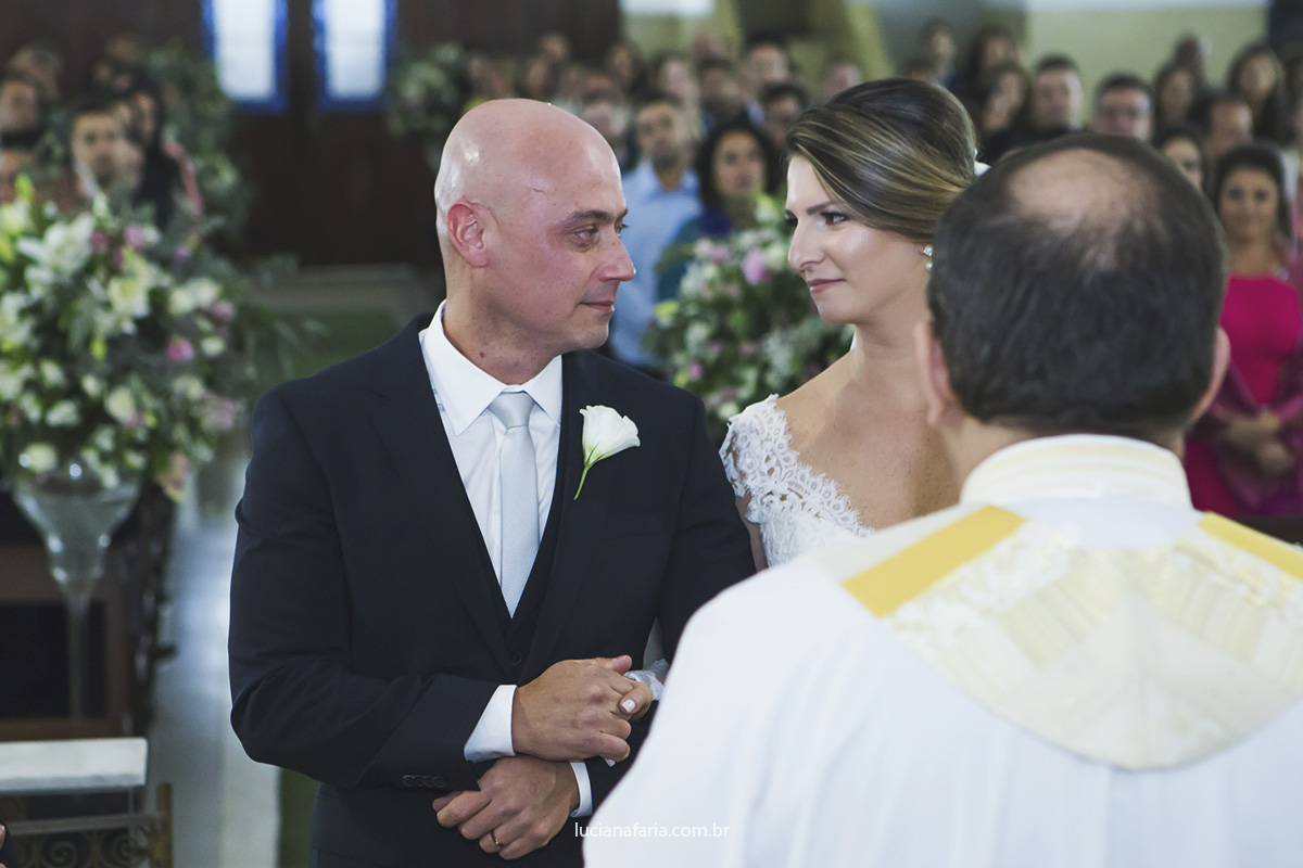 olhar apaixonado dos noivos na igreja decorada com flores tapete verde fotografias de casamento em minas gerais