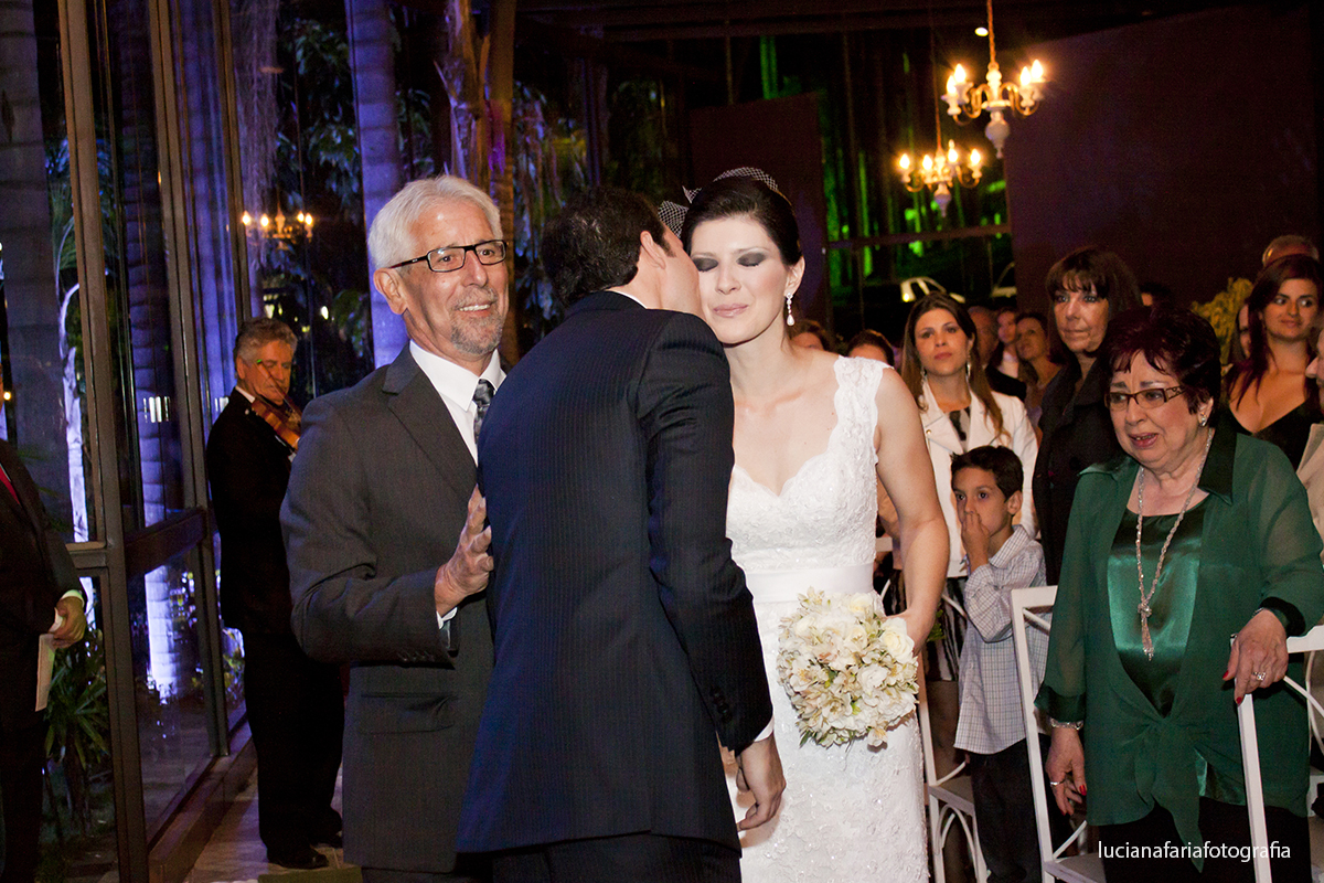 noiva com vestido de renda francesa voillete no cabelo encontra o noivo no corredor do salão villa la farme em minas gerais