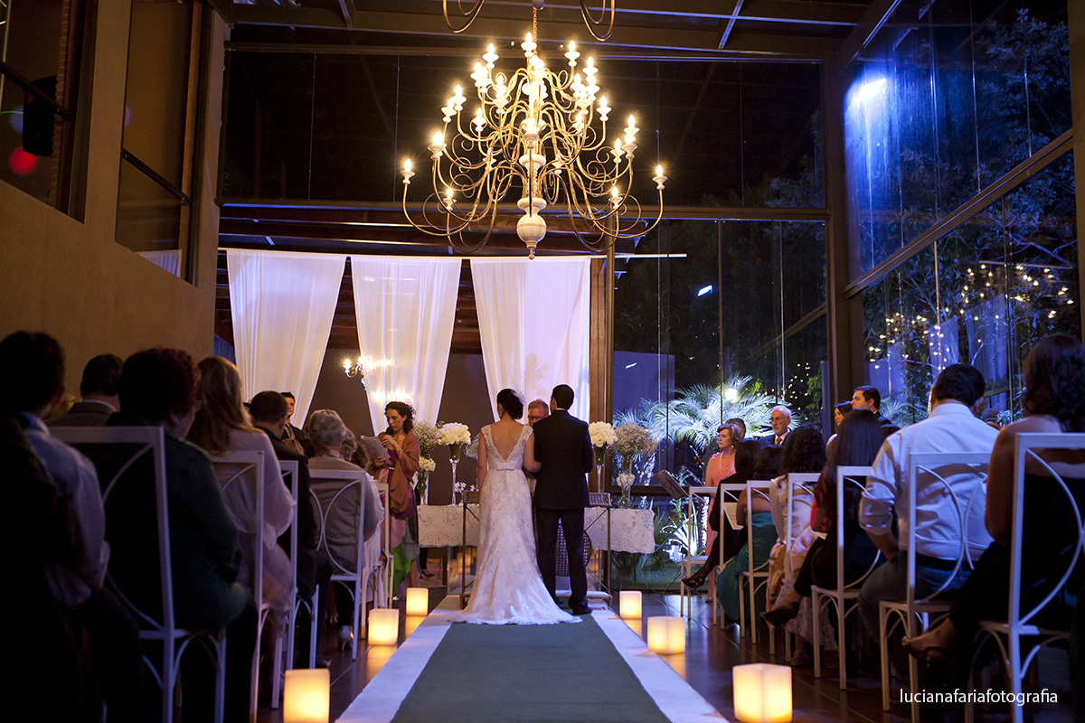 fotografia de trás do salão aparecendo os lustres de baixo com decoração de velas no chão tapete verde