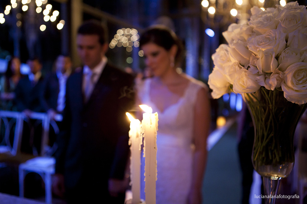 velas no altar com lindas flores brancas salão decorado com copos de lite e lisiantos brancos velas acesa deixa local iluminado