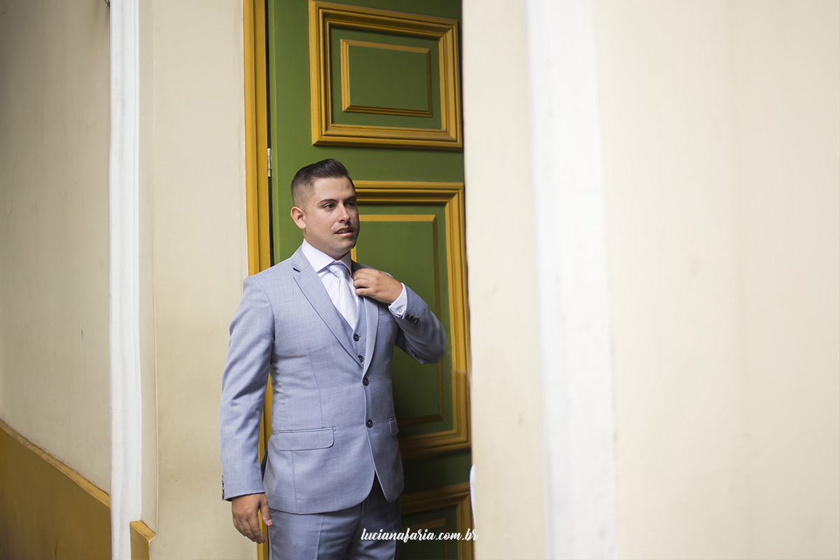 noivo na porta da capela santo antônio em poços de caldas casamento de dia na capela do centro da cidade com fotografias de casamento de dia da fotógrafa luciana faria que também faz fotografias de família