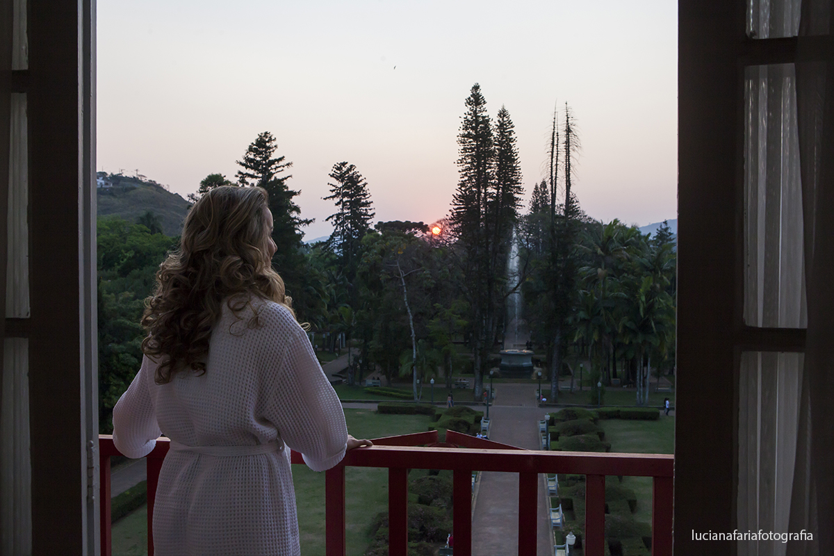 noiva apreciando um lindo por do sol em Poços de Caldas MG  no dia do casamento momento feliz registrado pela fotógrafa Luciana Faria na janela de frente para o jardim
