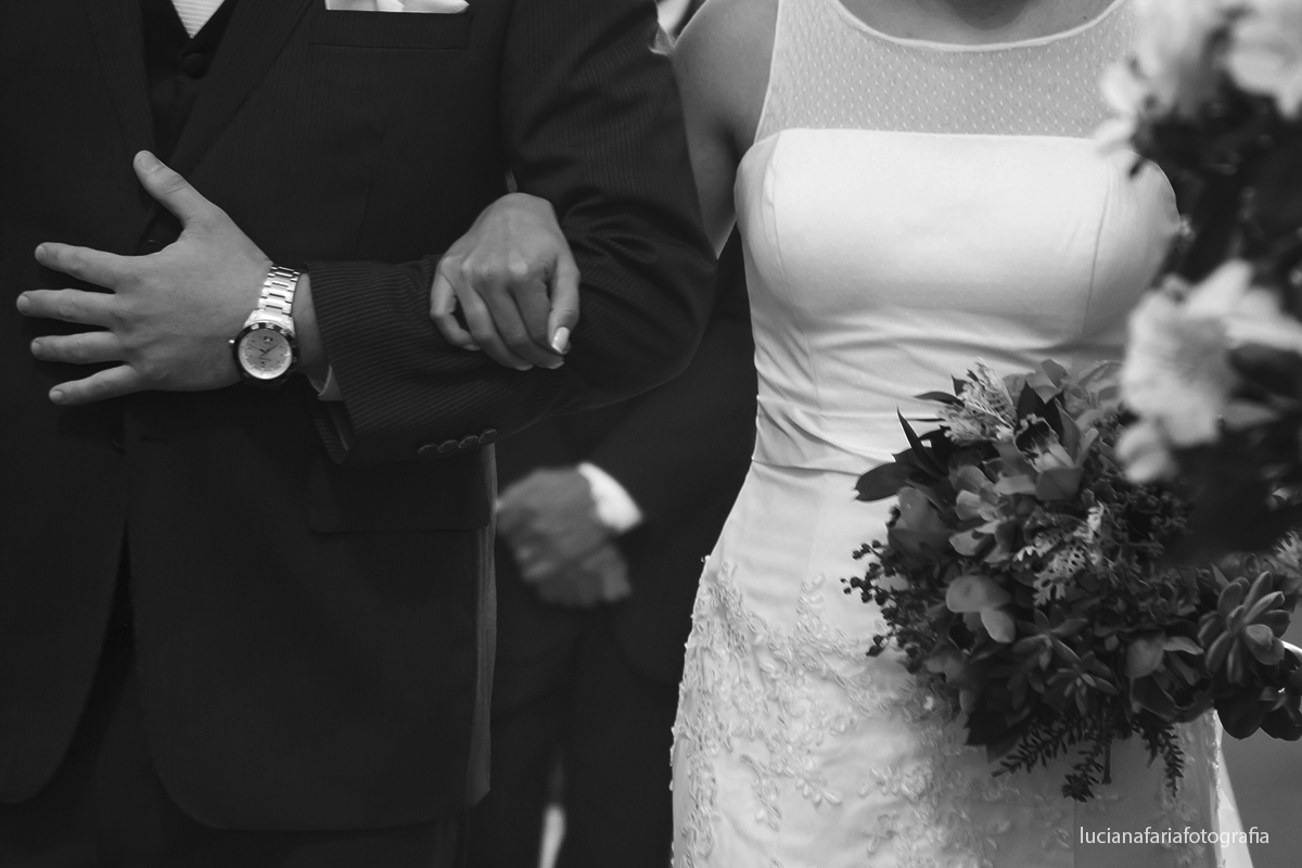 detalhe das mão unidas dos noivos com o pai no segundo plano buque da noiva maravilhoso