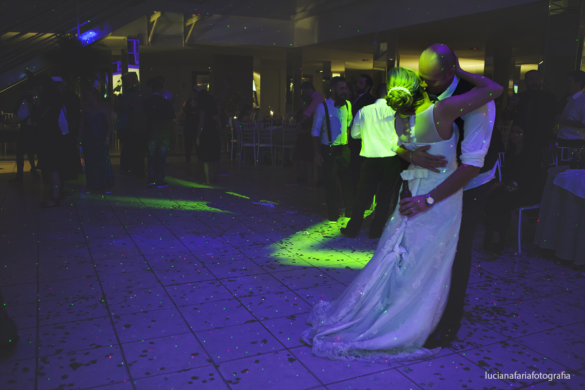 fim da festa noivos se abraçando no meio da pista de dança toda iluminada de verde e azul