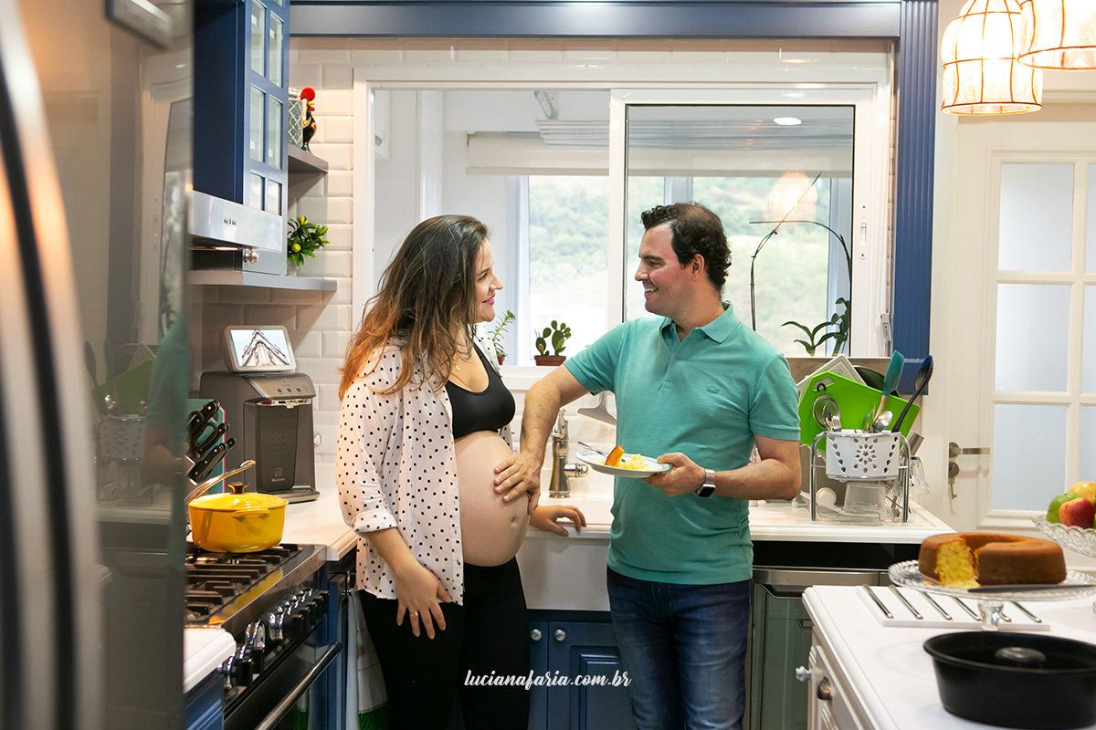 casal posa para fotografias de gestante na cozinha dao seu apartamento em poços de caldas a fotógrafa luciana faria registrou o momento do casal dividindo um pedaço de bolo de laranja