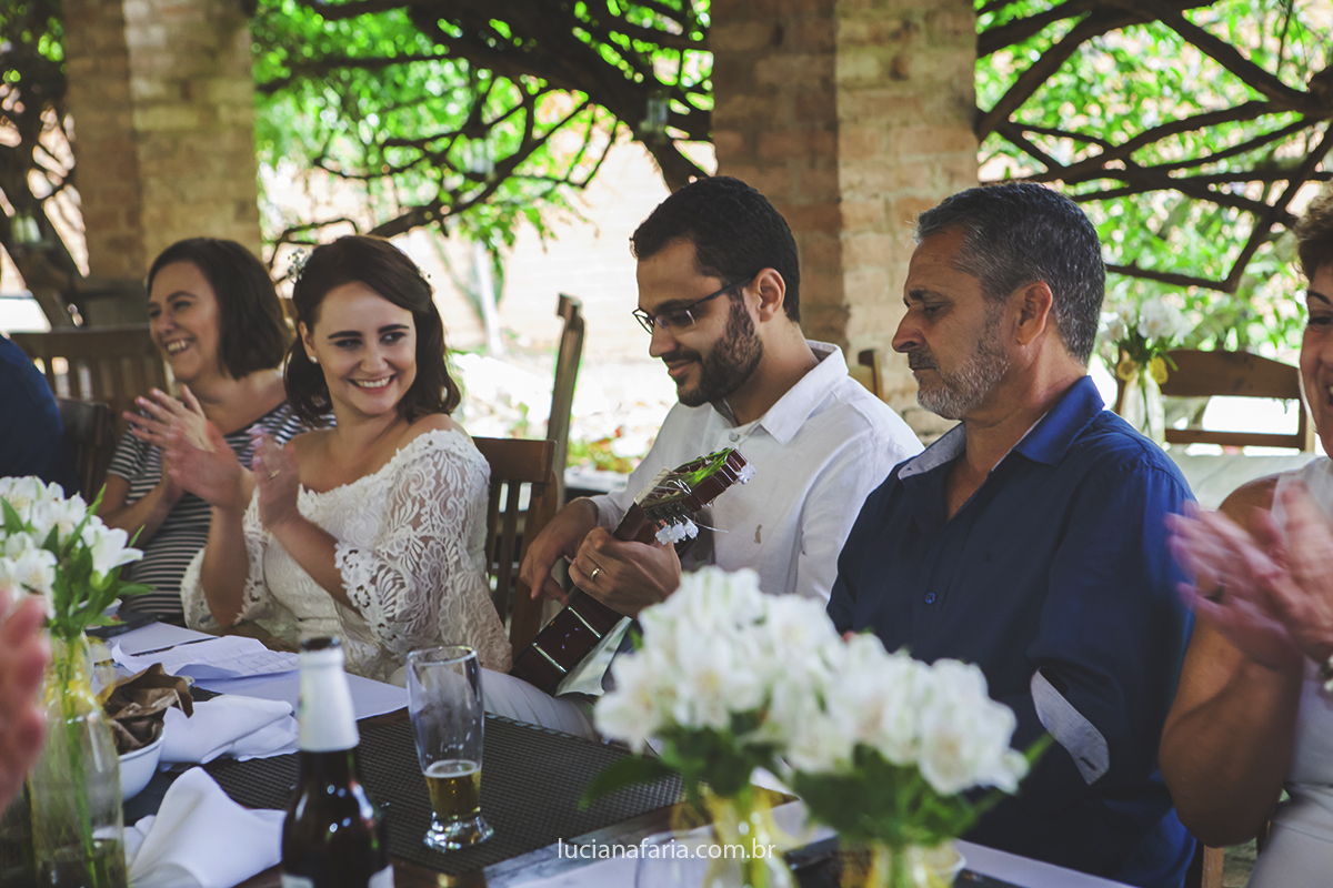 cantando para a noiva família ouve a musica do casal sentados a mesa