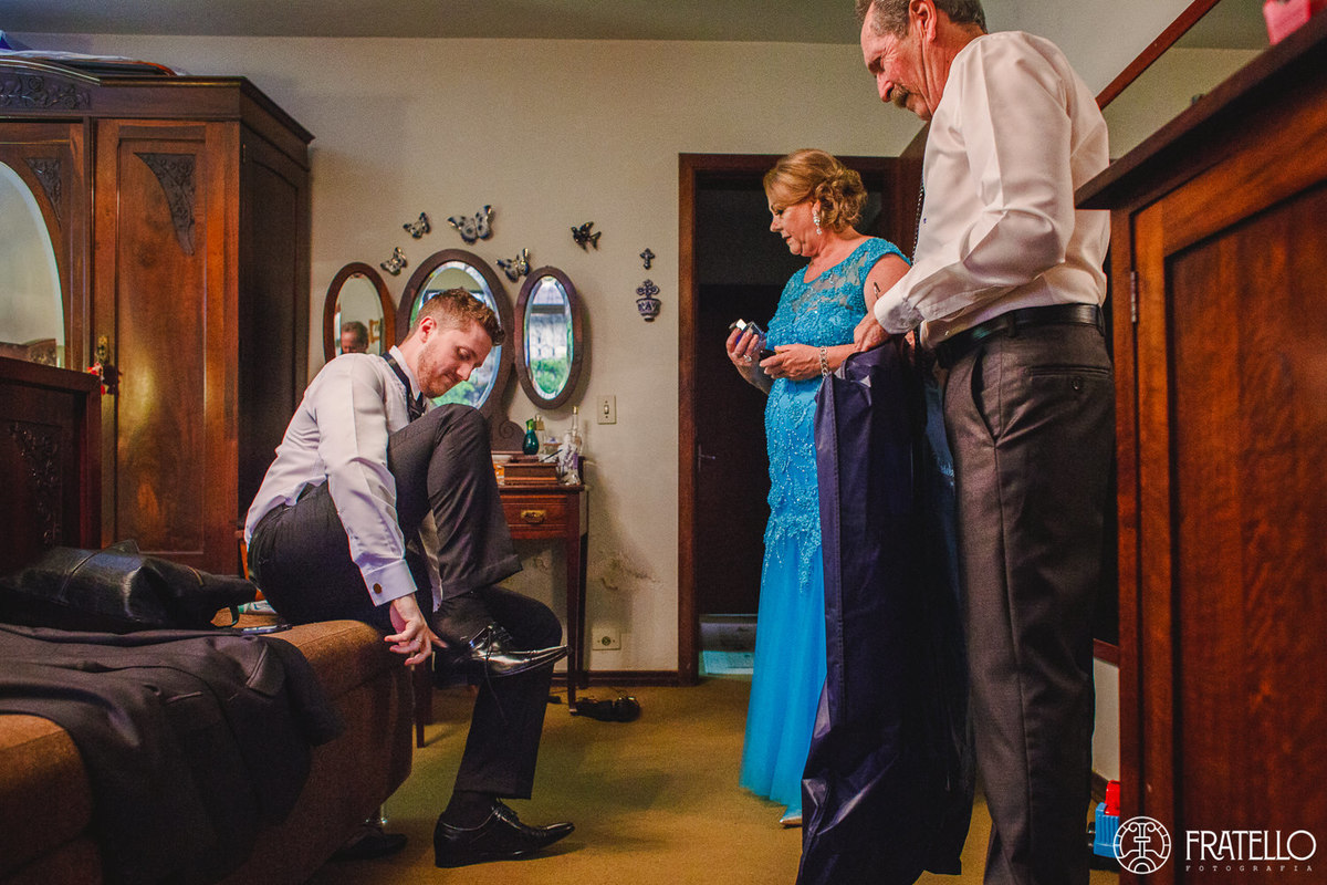 mae e pai do noivo observam o noivo colocando sapato no making of na casa do noivo