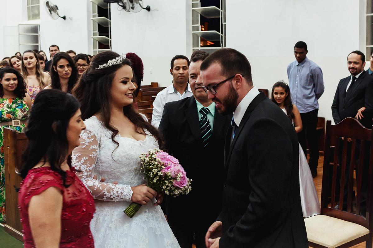 Noiva se encontrando com noivo no casamento ao lado da mãe do noivo.