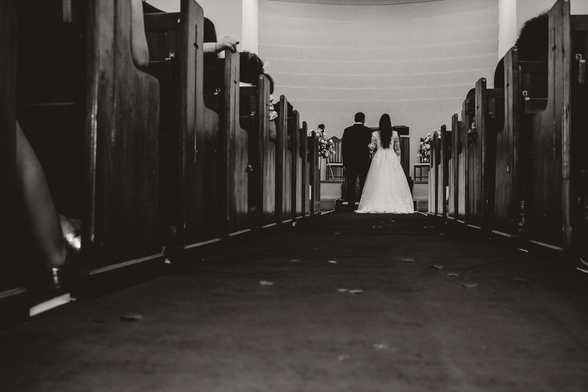 Foto do corredor com noivos ao fundo em igreja em carmo do paranaíba