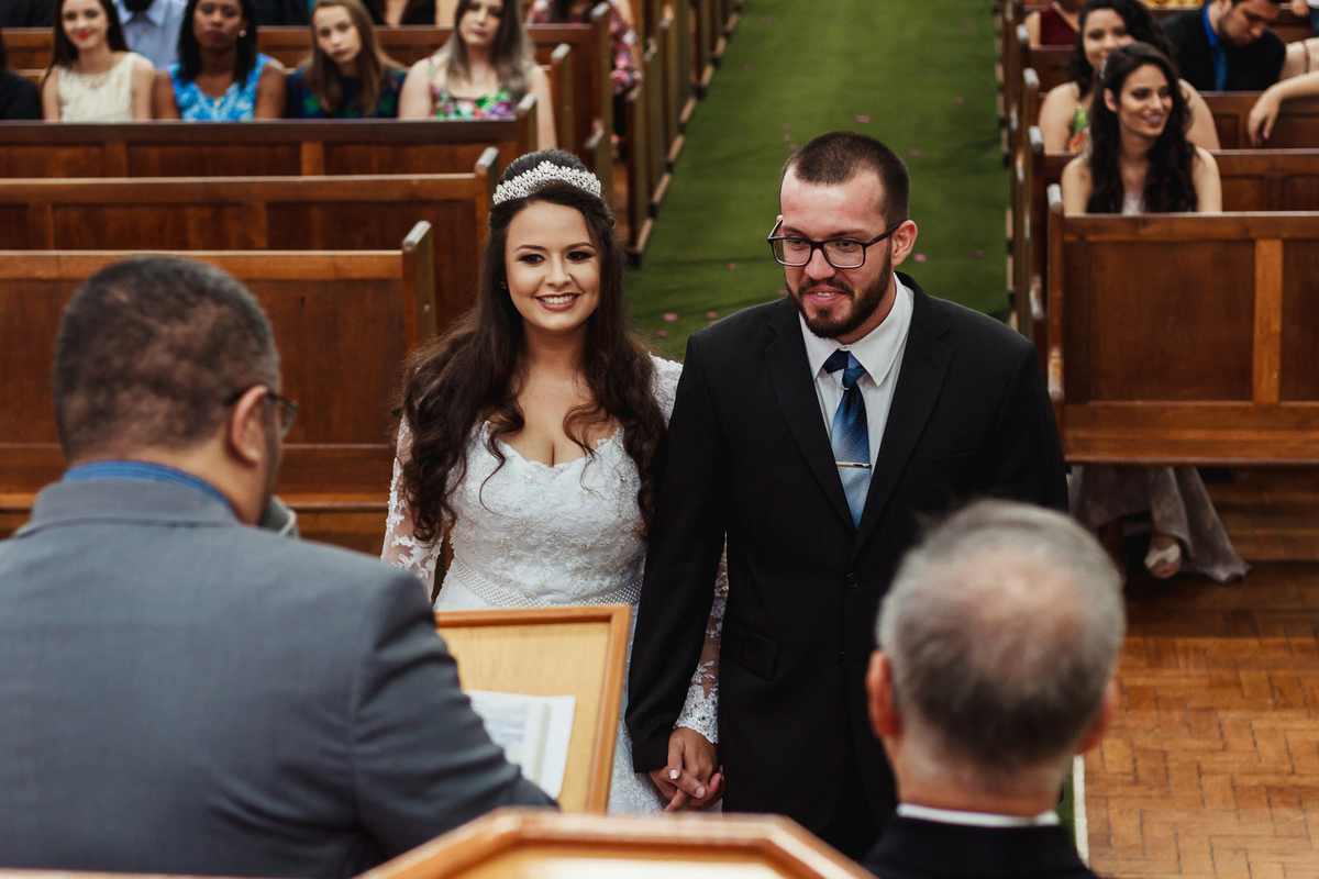 Noivos sorrindo para os pastores na cerimônia de casamento